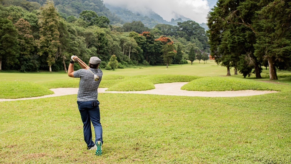 A man hitting a golf ball on an open green.