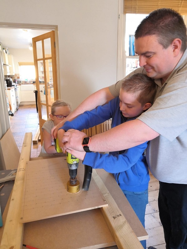 Oliver drilling a hole in the backboard